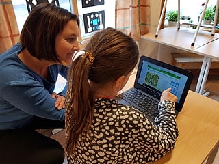 Kvinne som hjelper en jente med en matteøvelse på en bærbar PC, som viser «Alle tellere»