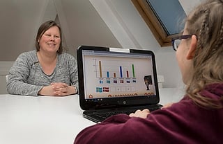 Kvinne som ser på en jente som bruker en bærbar PC og viser et søylediagram med flaggikoner